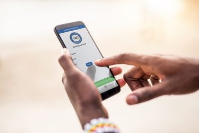 African man using phone on a beach.