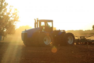 Agriculture: Farmer in tractor plowing a field with lens flare