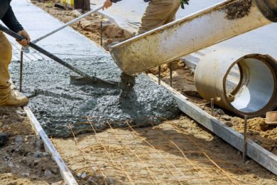 Cement truck mixer pouring fresh concrete in reinforced cement sidewalk
